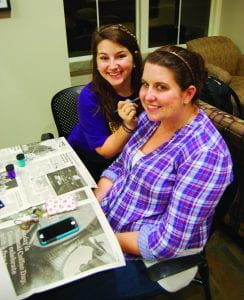 Junior Deanna Walker paints the face of senior Jenny Connor at the ADPi table.
