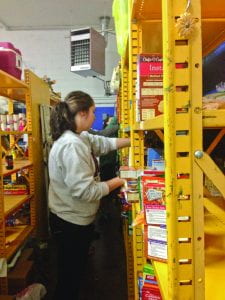 Senior Krissy Raque stocks shelves at the Catholic Action Center this past Saturday.