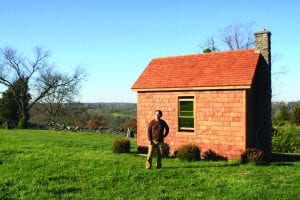 Centre graduate and professor Mark Lucas stands with his self-built cabin which was completed in the spring of 2013.