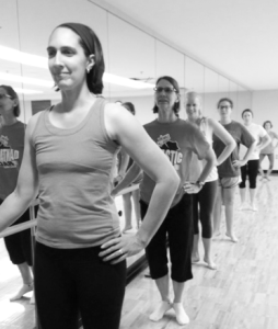 Settles leads a barre fitness class, mixing ballet dance techniques with yoga and pilatees.