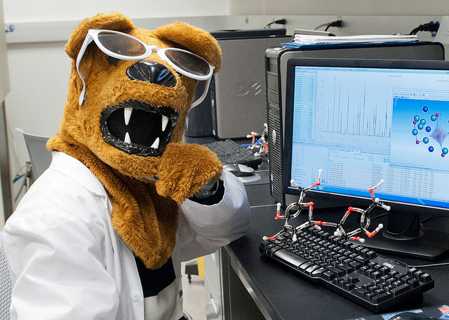 Penn State Nittany Lion in a lab coat, sitting at a computer.
