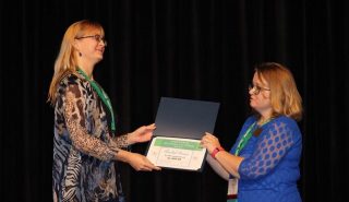 Rachel Gerner, left, receives the master’s student award from Tricia Kerr, ARKTESOL president.