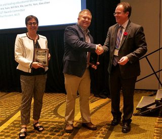 Dennis Beck, center, is congratulated by Eugene Kowach, president of the Association for Educational Communications and Technology. Mahnaz Moallem, left, of the University of North Carolina Wilmington, also received an award.