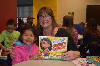 University of Arkansas student Mattie Milani gives a book to the third-grade student she tutored this semester.