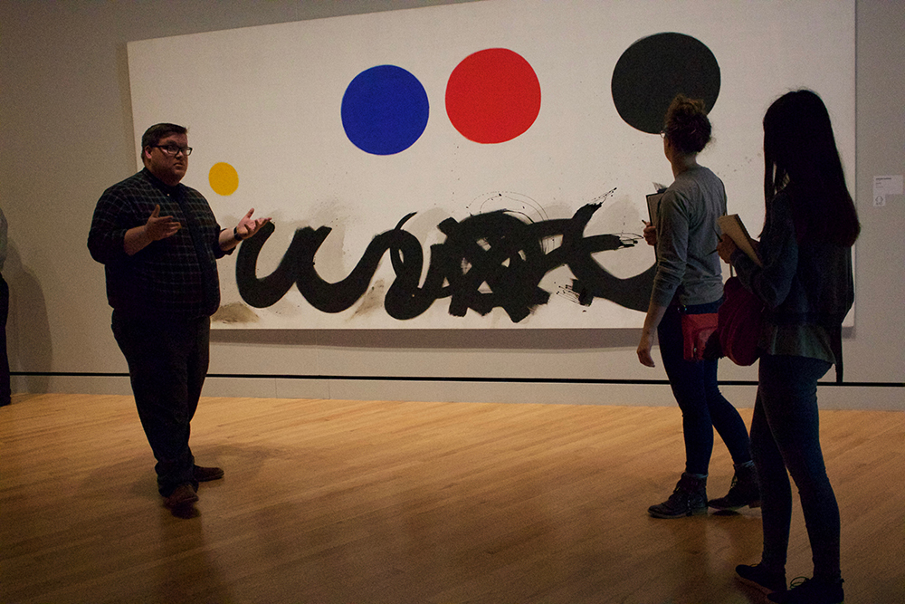 Docent and students examine large abstract painting. 