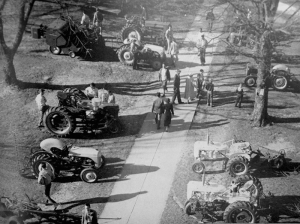 old photo of people walking between rows of tractors