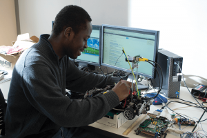 a young man is working on a remote control car in front of a monitor