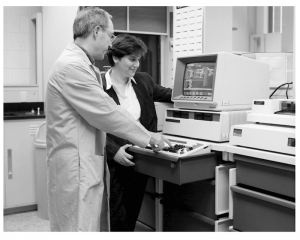 two people stand in front of an eighties-era computer