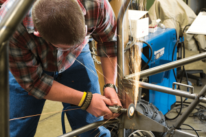 a student uses a tool on the chasis of a vechicle