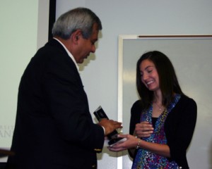 A woman accepts an award from a man