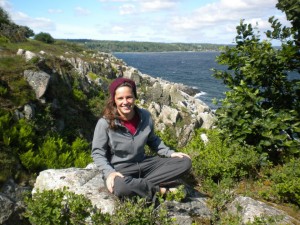 A girl sitting on a mountain with the ocean in the background