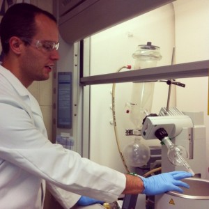 student working with a machine under a lab hood