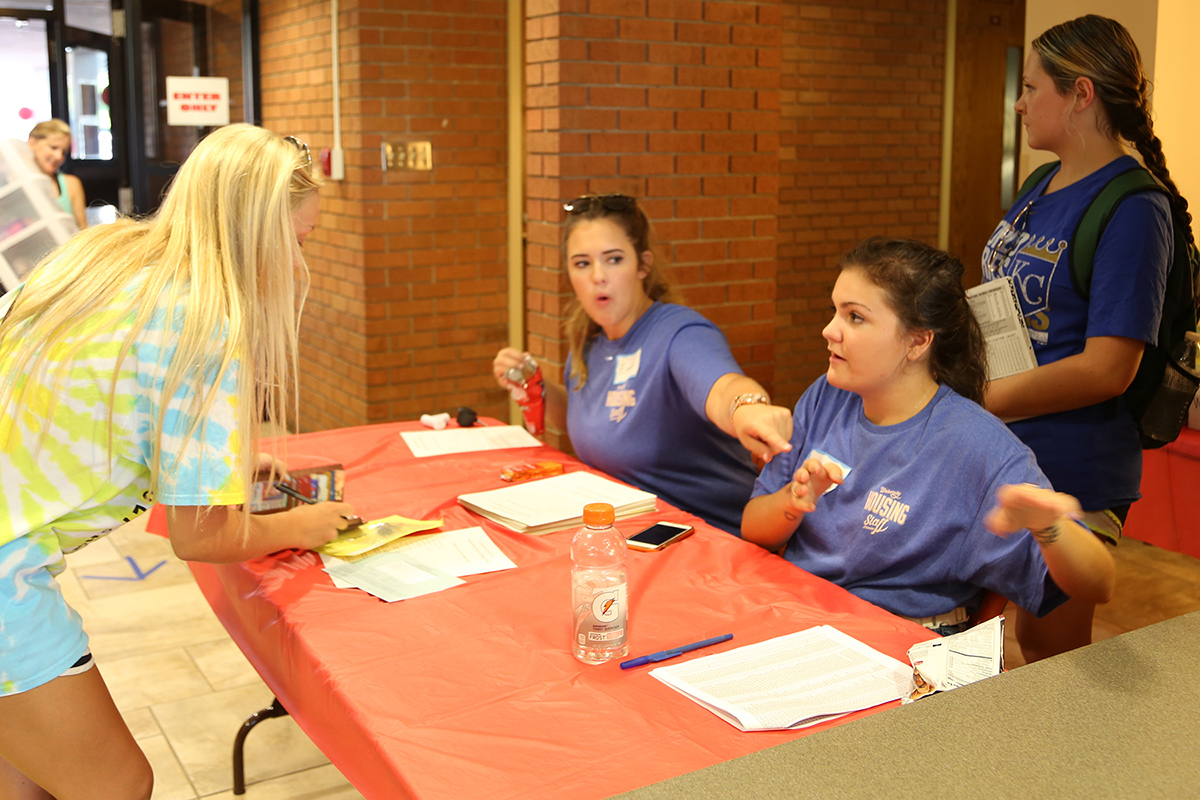 Emma Menard and Bailey French motion a student to her next step in the check-in process.