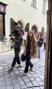 The crew walks down the street with heavy equipment to shoot some outdoor scenes