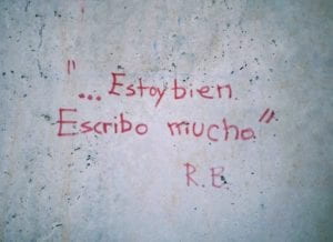 Sobre una pared, pintado en rotulador rojo: "Estoy bien, escribo mucho"