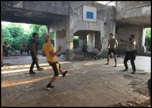 Un voluntario y tres migrantes juegan al voleibol en la sale del squat que sirve de comedor