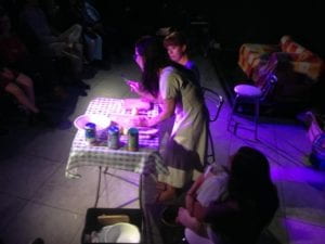 woman on the stage in front of a chair, under purple light