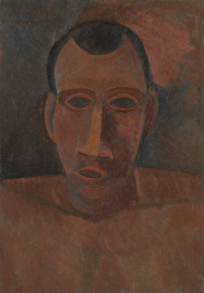 Rendered in muted brown, red, and orange tones, Pablo Picasso’s Portrait of a Man depicts a nude male from the chest up; with geometrically rendered facial features, open mouth, a pronounced triangular nose, empty, almond shaped black eyes and short brown hair. The figure holds a direct gaze and appears to be leaning forward slightly. The background consists of indistinct green, orange, and brown sections of color which blend together. 