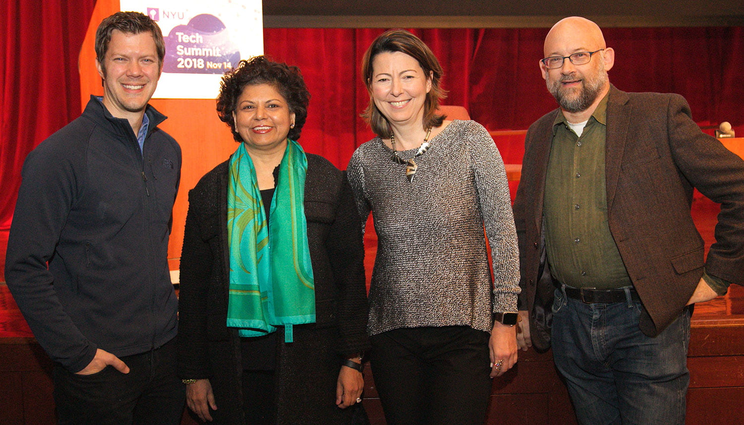 Speakers posing in front of a red curtain