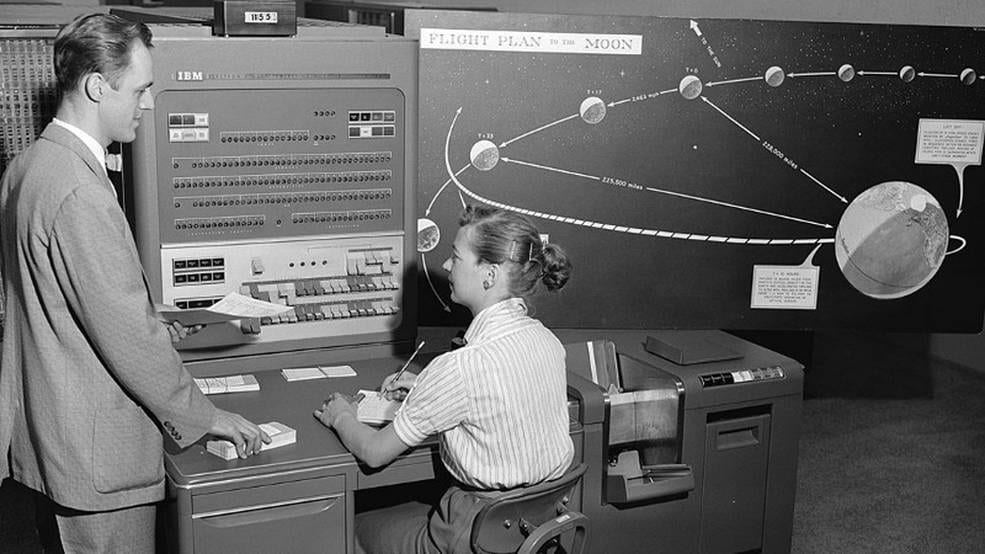 A man and a woman at a large IBM 70v computer console in a NASA office