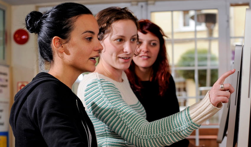 three people pointing at a computer screen