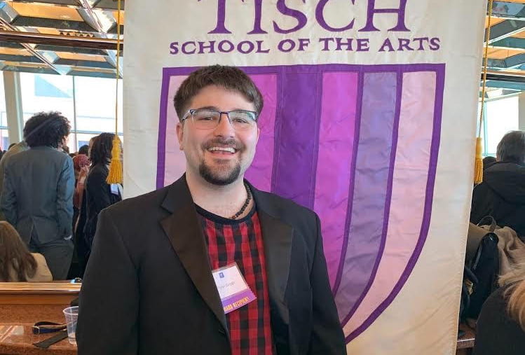 Ryan Grippi in front of a Tisch School of the Arts flag