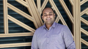 Photo of Navajit in front of a wooden pattern.