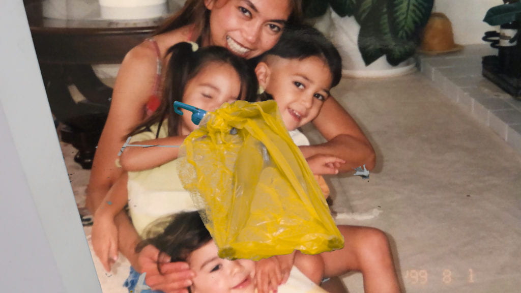 Image of women with three kids hugging on floor.