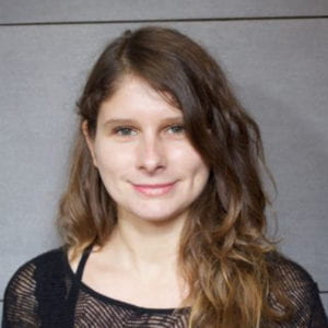 Allyson Paty smiling. She is standing against a gray backdrop.