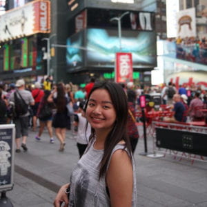 Kristi Wong standing in Times Square. The blurred background is busy with many people and bright screens.