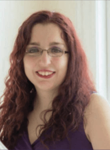 Color portrait of Amy Gravino on a white background, wearing glasses and a purple shirt.