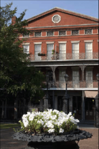 3 Story red brick building with white flowers in foreground.