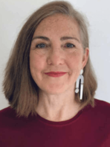 Color portrait of Merilee Mostov on a white background, wearing a maroon shirt.