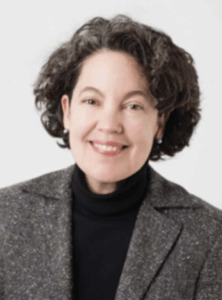 Color portrait of Patricia Pongracz on a white background, wearing a black turtleneck and grey blazer.