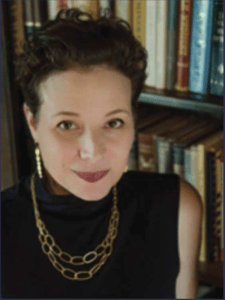 Color portrait of Rosanna Flouty in front of a bookshelf, wearing a black shirt and gold chain necklace.