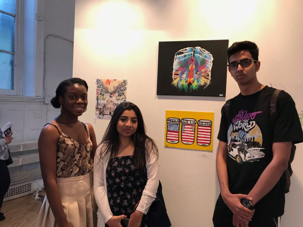 Students posing in front of artwork at the opening exhibition