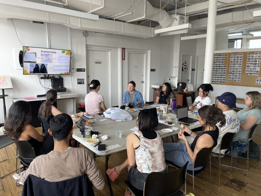 Photograph of classroom with students sitting around a table talking