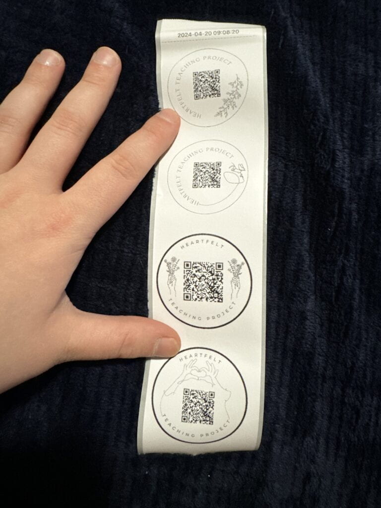 Photograph of a hand holding a group of stickers with QR codes