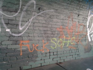 Brick wall with graffiti reading "fuck soho"