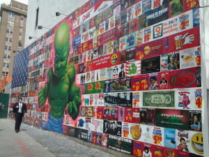 Mural with american flag made out of pop culture images in background and a green hulk-like child in the foreground