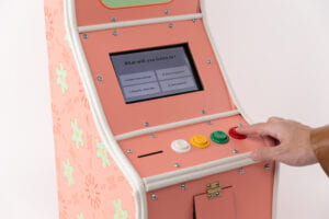 Close up 3/4 View of the Title "Bon Appetit" on the game consoleas a hand presses the red D button on the far left of the console