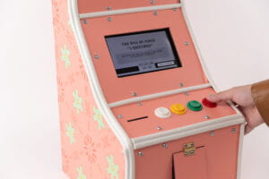 Close up 3/4 View of the Title "Bon Appetit" on the game console as a hand presses the red D button on the far left of the console