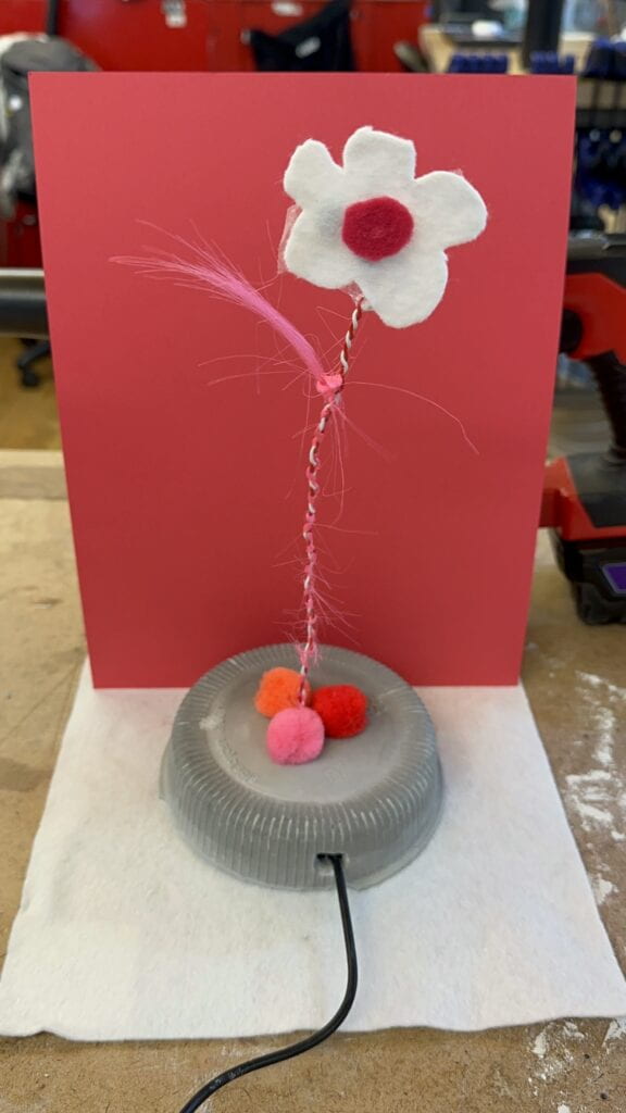 Final form of object with added white felt flower with vibration haptic motor attached on the back