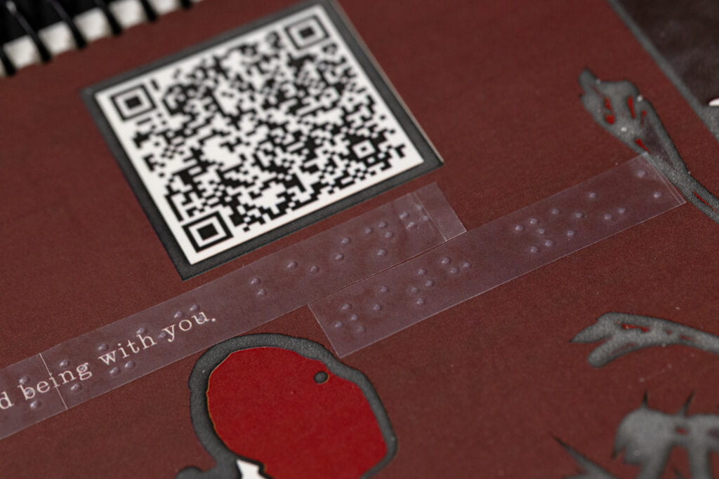 A page of a book with text with clear braille label on top, tactile graphics and qr codes