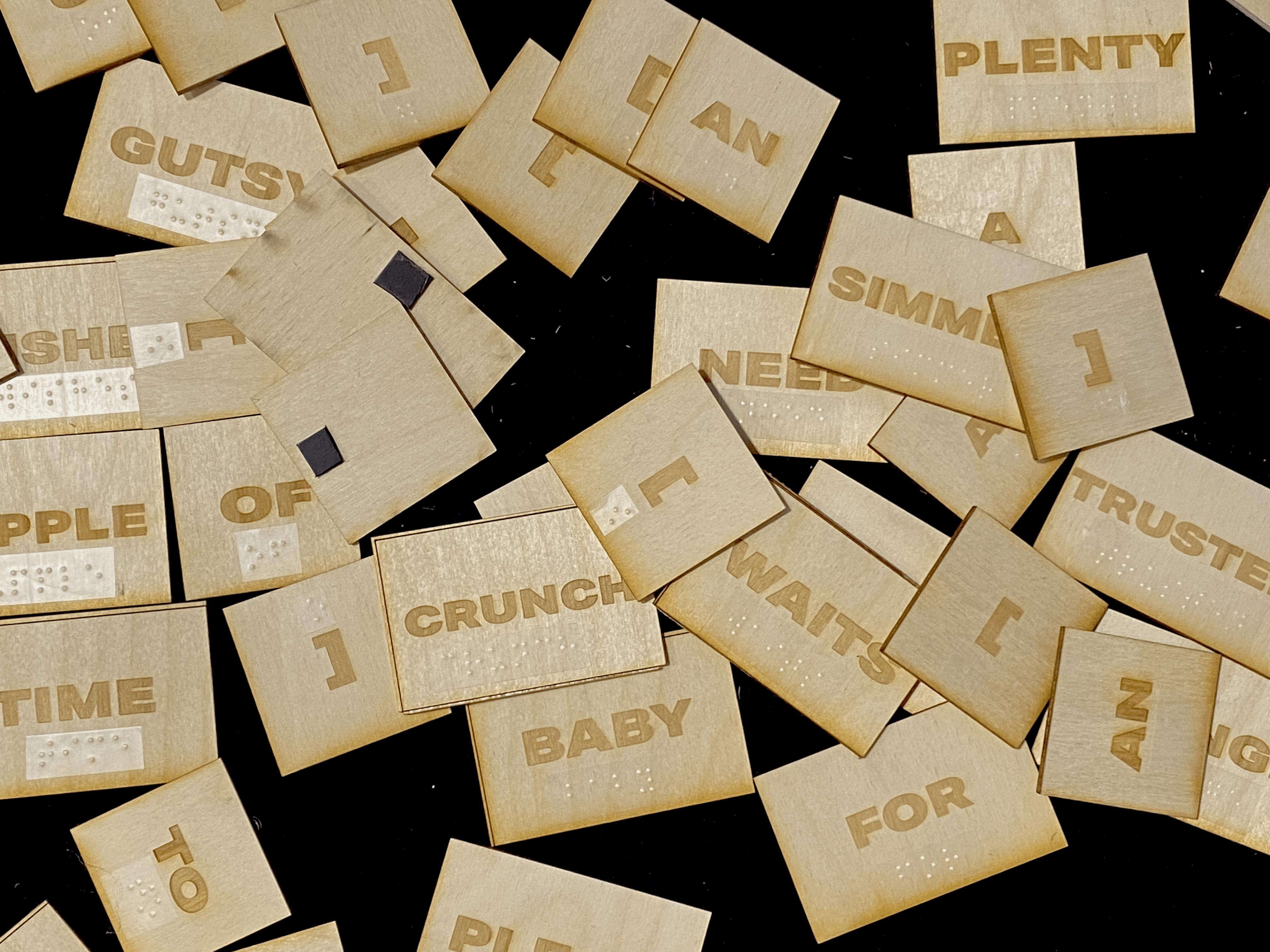 a collection of laser etched wooden tiles with words engraved into it. They have braille labels on it.