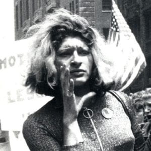 Sylvia Rivera with banner; click on image to launch a Vimeo recording of her 1973 speech at Washington Square Park.