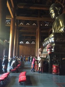 people inside temple with large Buddha statue