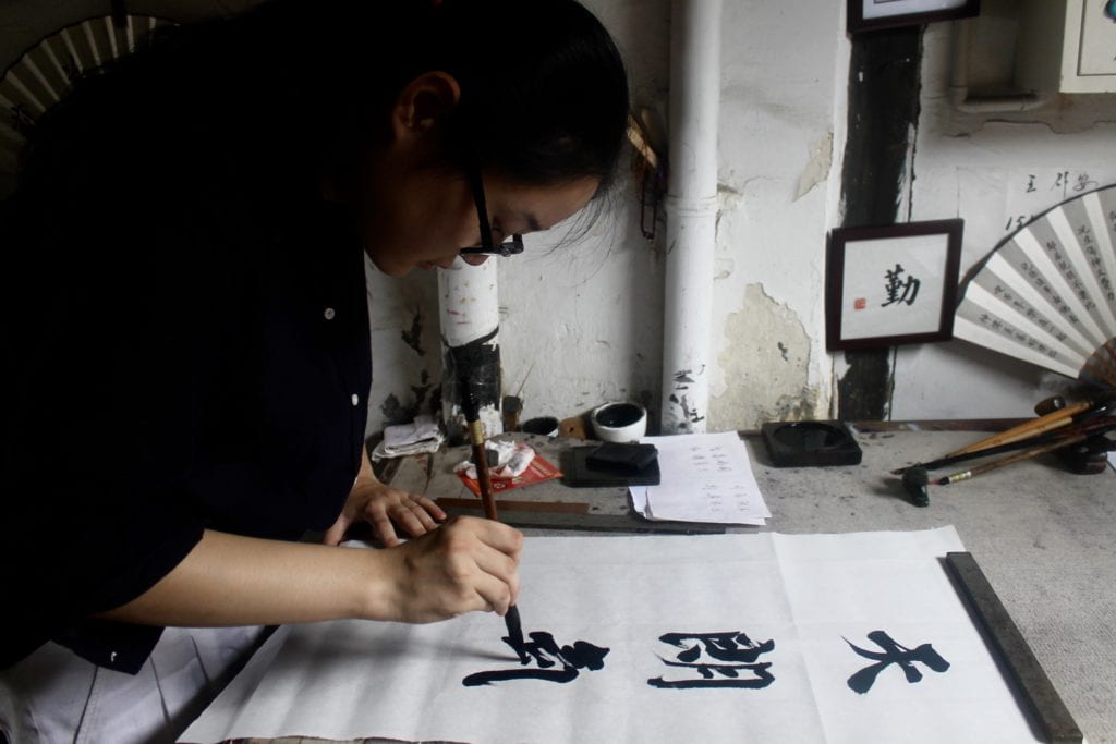 woman writing in Chinese calligraphy