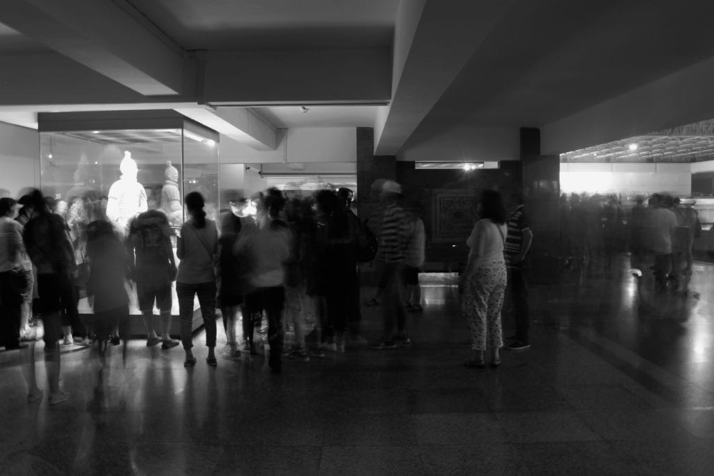 people looking at terra cotta statues in museum 