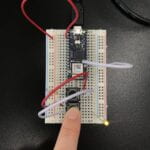 a breadboard with an Arduino Nano connected to 2 pushbuttons and a LED light - one button pressed